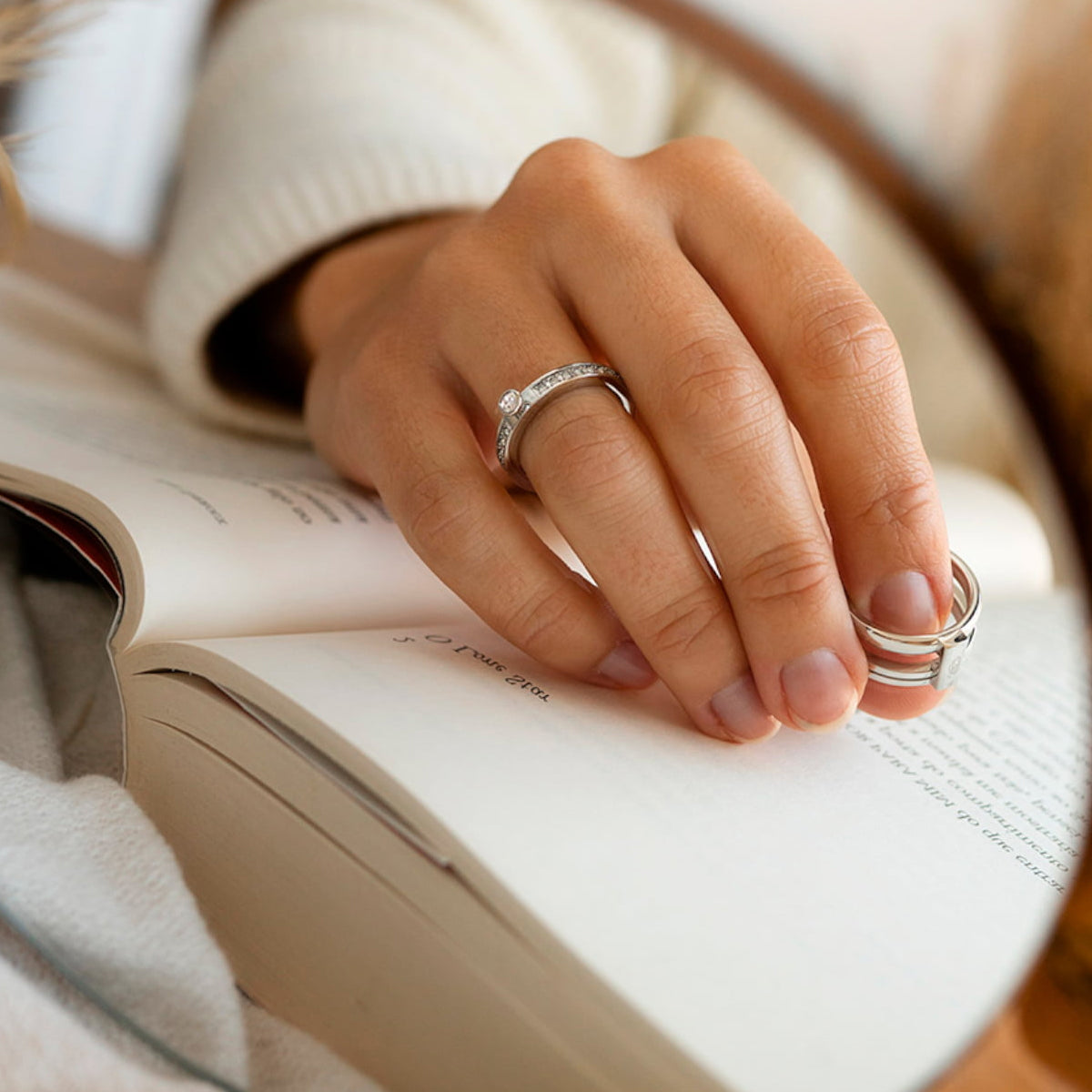 Close-up of elegant rings on a hand holding a book, featuring AN JEWELS JEWELRY Mod. AR.R1NS01SC-9, showcasing timeless elegance.