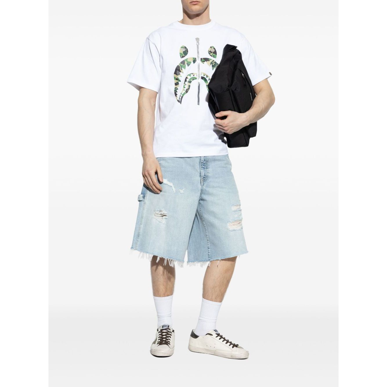 Model wearing Golden Goose Super-Star in nappa leather with leather star and leather heel tab sneakers, denim shorts, and white t-shirt.