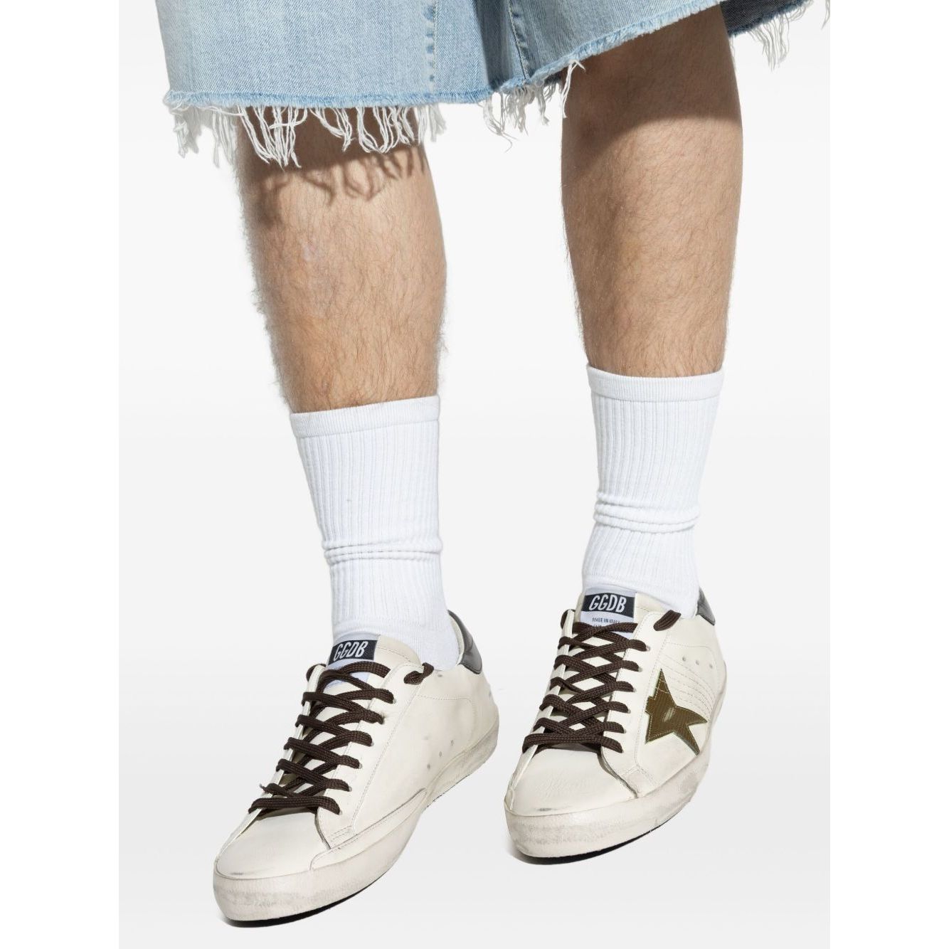 Golden Goose Super-Star in nappa leather with leather star and leather heel tab, white sneakers with lace-up and star detail, worn with denim.