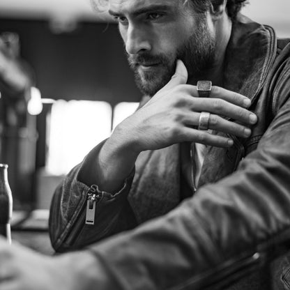 Man wearing leather jacket with rings, sitting thoughtfully