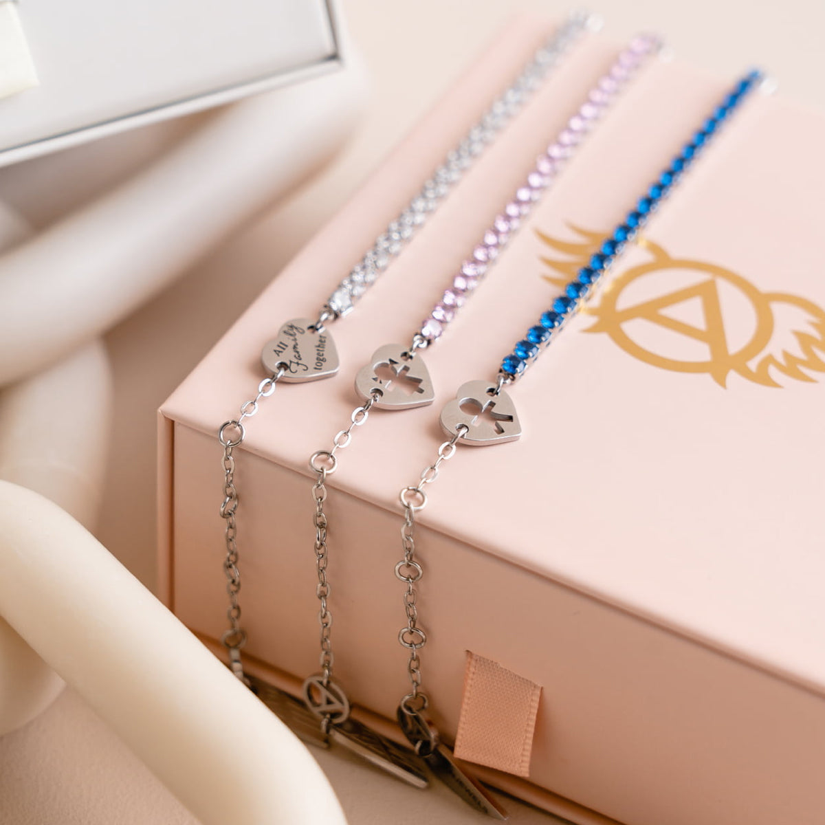 AN JEWELS JEWELRY Mod. AL.BLIYMBL showing elegant bracelets with heart charms on a decorative box.