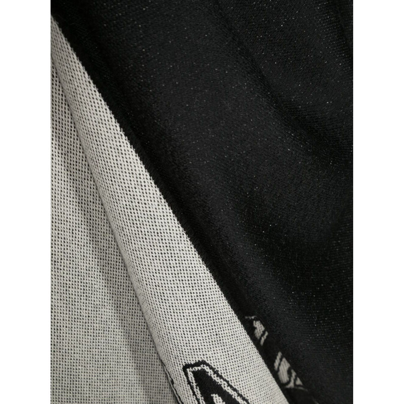 Close-up of black Alexander McQueen Logo wool scarf with logo and skull print, featuring frayed hem detail.