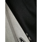 Close-up of black Alexander McQueen Logo wool scarf with logo and skull print, featuring frayed hem detail.