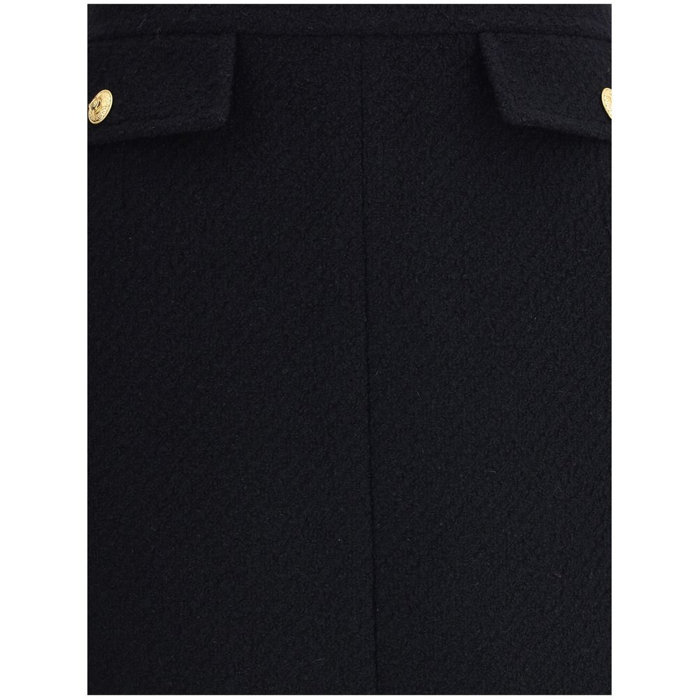 Close-up of Chloé Black Wool Midi Skirt with gold-tone buttons on front flap pockets, crafted from premium bouclé wool.